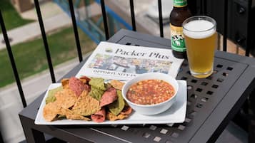 Ein Tisch mit Nachos, einer Salsa-Schale, einem Bierglas und einer Bierflasche auf einem Balkon.