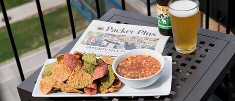 Ein Tisch mit Nachos, einer Salsa-Schale, einem Bierglas und einer Bierflasche auf einem Balkon.