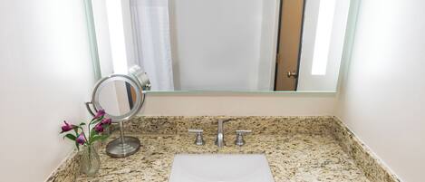 A bathroom with a granite countertop, a sink, a mirror, and a towel rack.