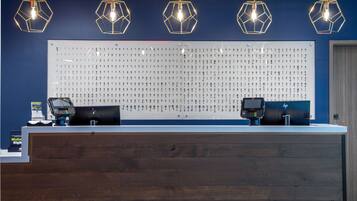 Una recepción con un panel de madera, un expositor de llaves en la pared y dos terminales de pago.