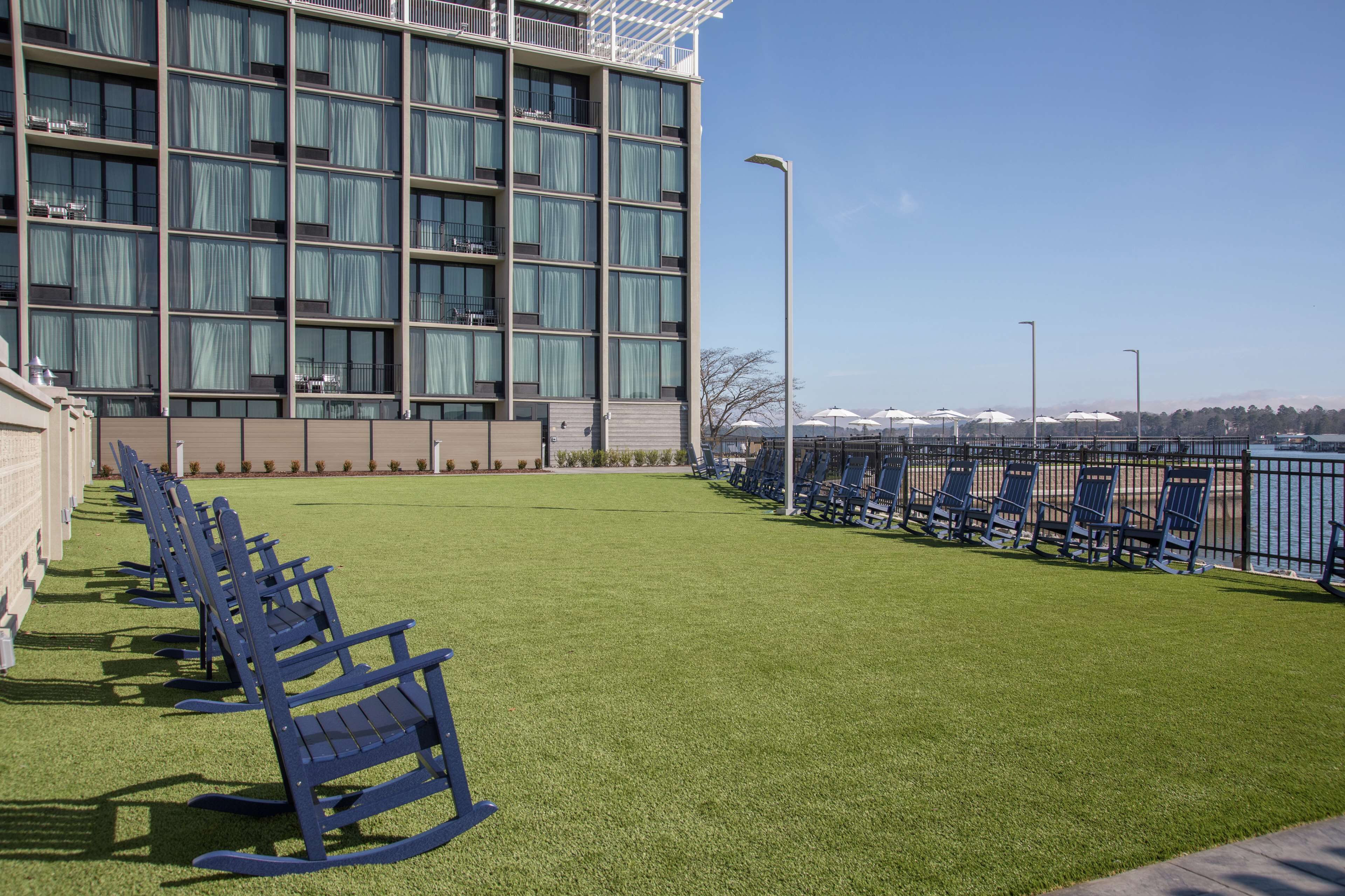 Ein Hotel mit Terrasse, blaue Schaukelstühle und Blick aufs Wasser.