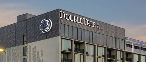 Un hotel DoubleTree by Hilton con fachada moderna, ventanas amplias y un área de entrada cubierta.