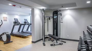 Ein Fitnessstudio mit Laufbändern, einer Gewichtbank und Kurzhanteln.