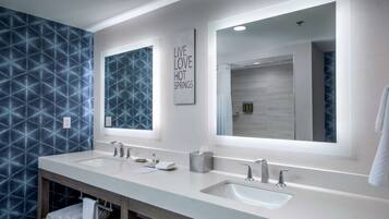 A modern bathroom with two sinks, a large mirror, and a geometric patterned wall.