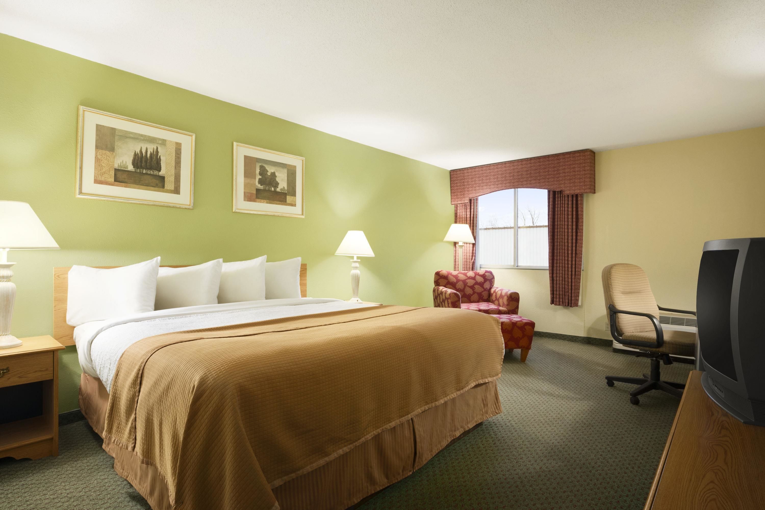 Une chambre d’hôtel avec un grand lit, deux lampes de chevet, une télévision, un bureau et une chaise.