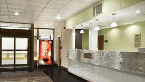 Un hall d’hôtel avec un distributeur automatique de Coca-Cola, un comptoir d’accueil et un tapis à motifs.