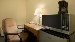 Une chambre d’hôtel équipée d’un four à micro-ondes, d’une machine à café, d’un bureau, d’une chaise et d’une lampe.