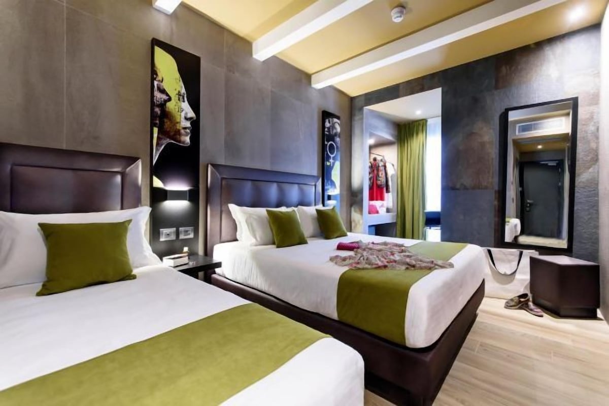A hotel room with two beds, a large mirror, and a wardrobe.