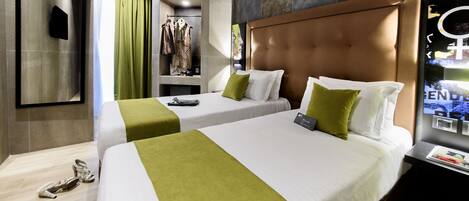Een hotelkamer met twee bedden, een spiegel, een kaptafel met spiegel en een kapstok met kleding eraan.