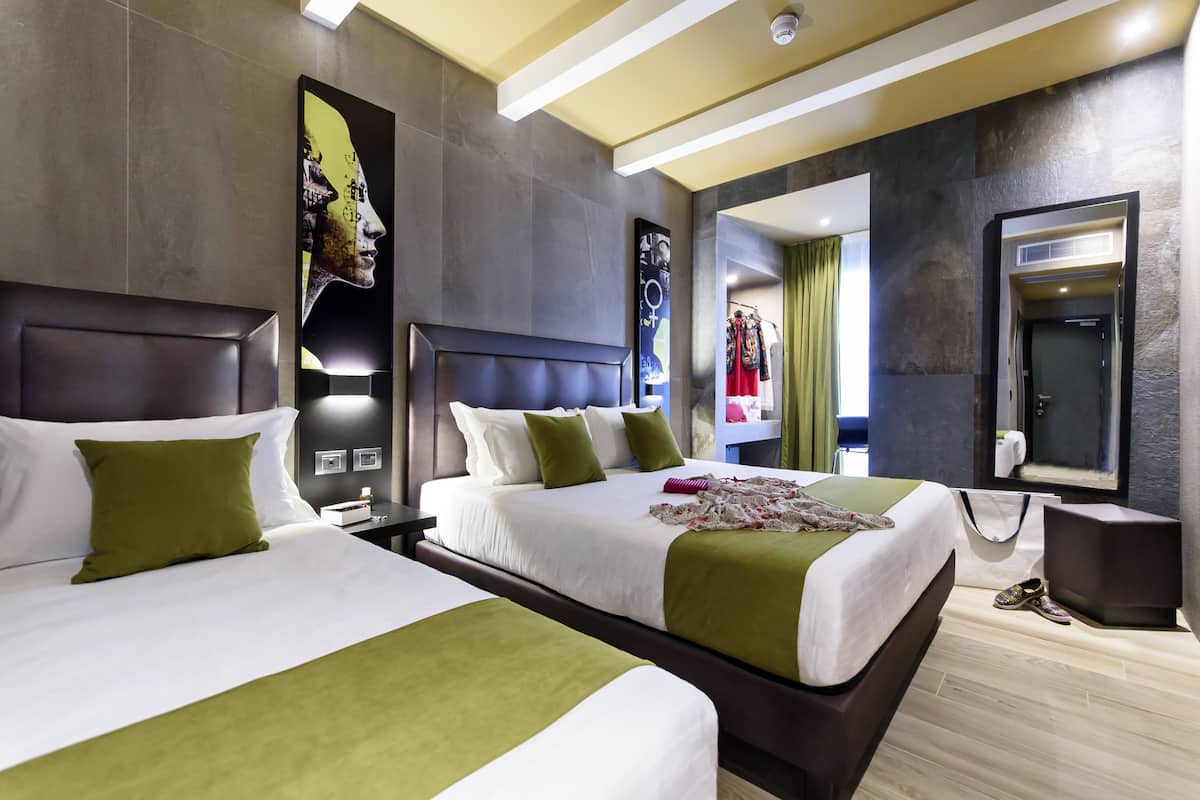 A modern hotel room with two beds, a large mirror, and a view of the hallway.