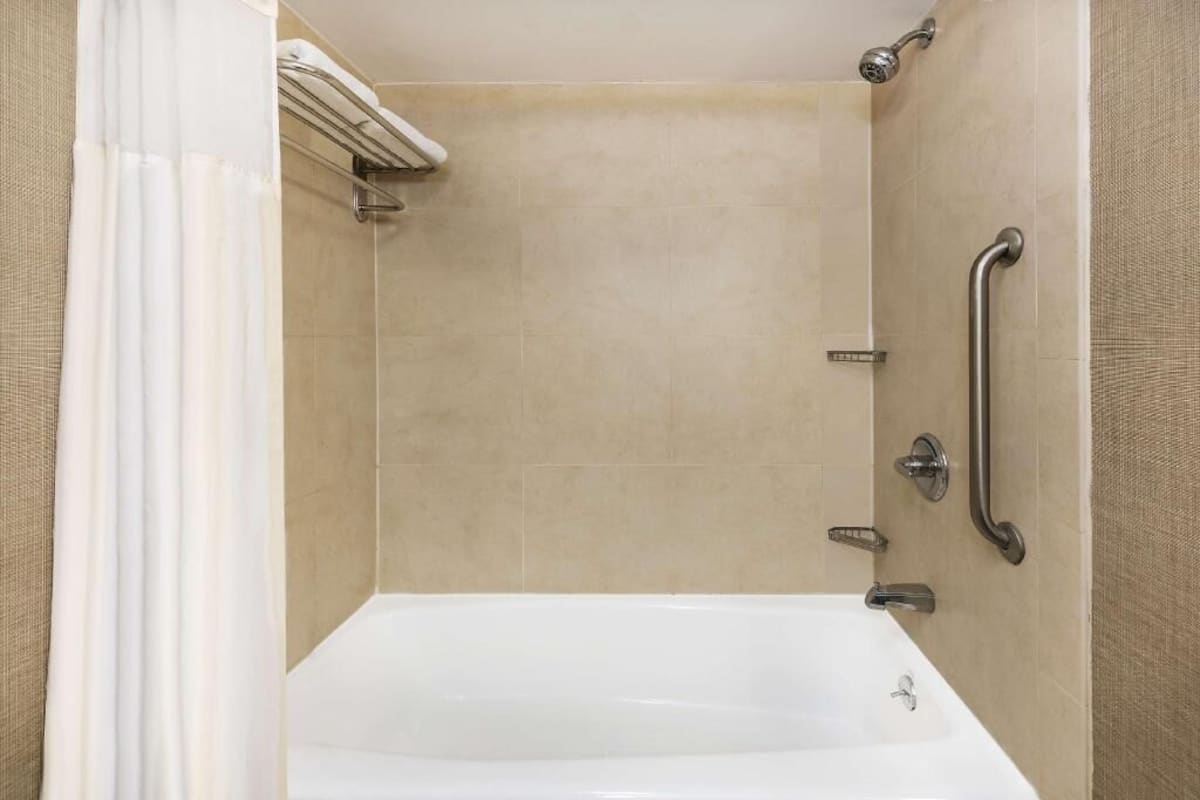 Une douche avec une baignoire, un porte-serviettes et une barre d’appui.