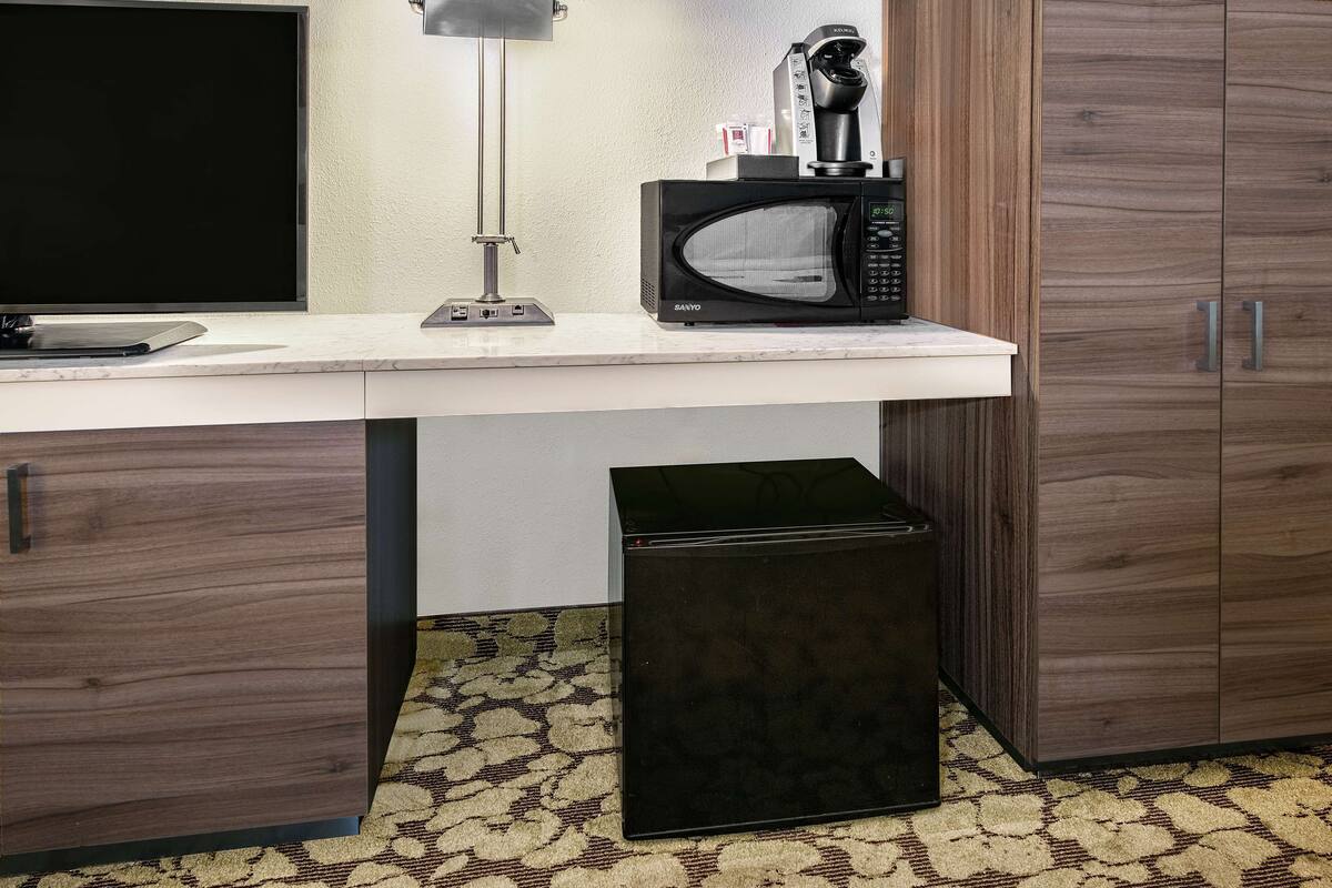A kitchen with a microwave, coffee maker, and a small refrigerator.