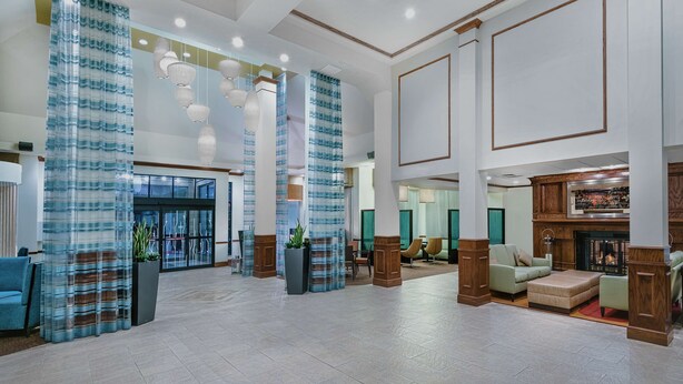Eine großzügige Lobby mit modernem Design, ausgestattet mit einer gemütlichen Sitzecke, einem Kamin und dekorativer Beleuchtung.