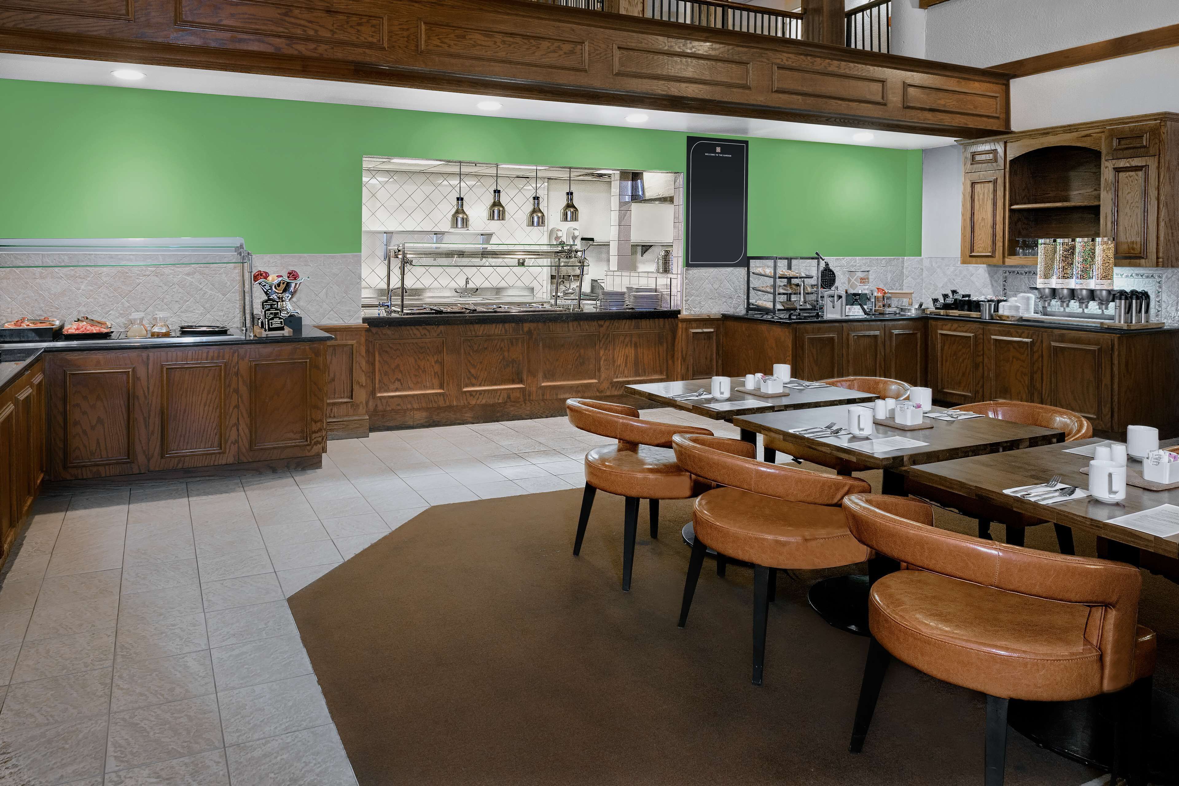 A restaurant with wooden cabinets, a buffet area, and brown leather chairs.
