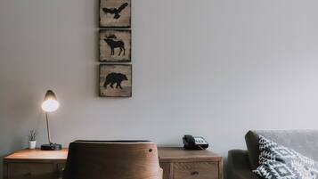 A wooden desk with a lamp, a chair, a phone, and a wall-mounted animal silhouette artwork.