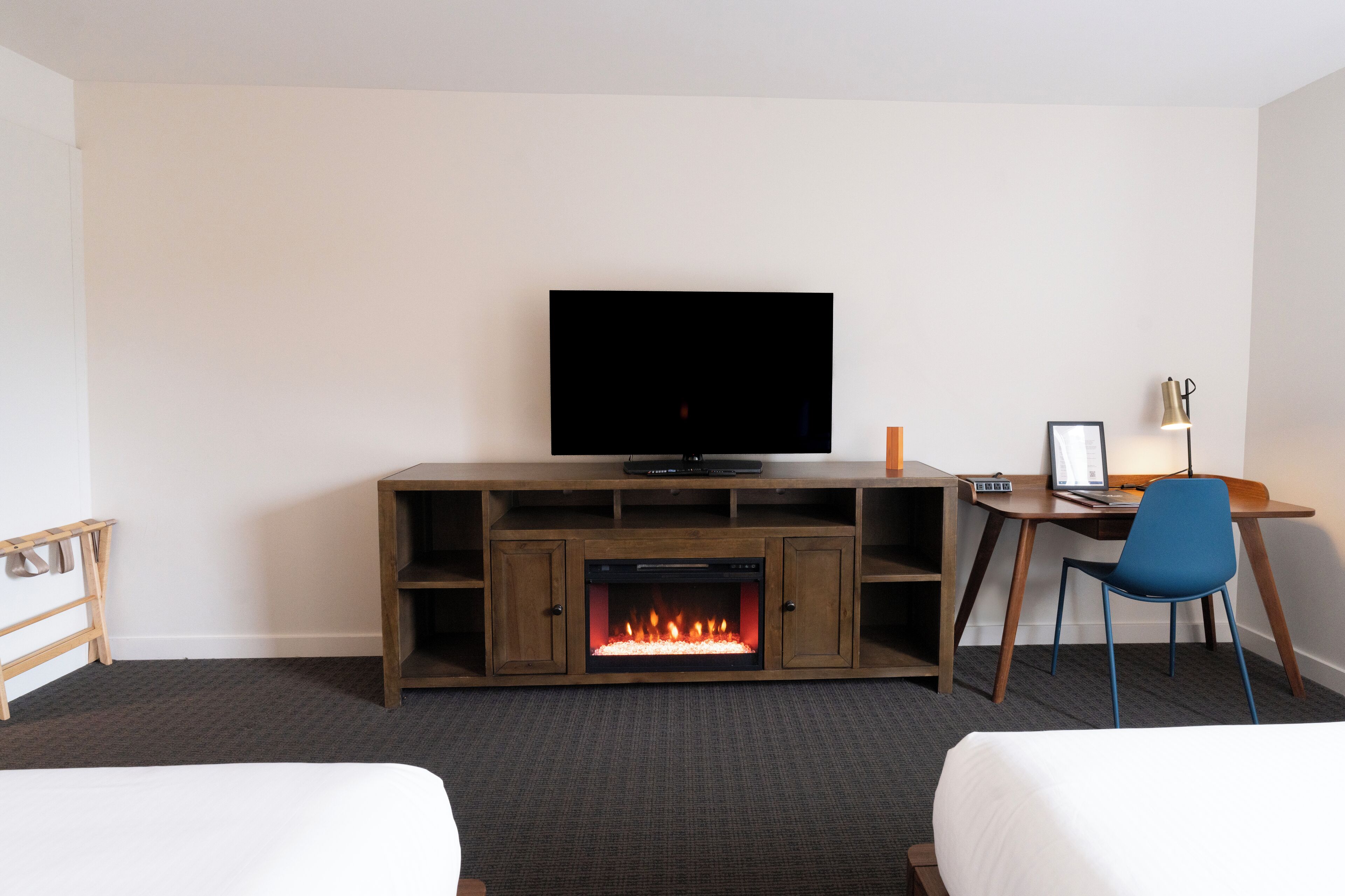 Ein Hotelzimmer mit Fernseher, Kamin, Schreibtisch und zwei Betten.