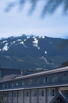 Un edificio con varias ventanas y techo inclinado, probablemente un hotel o una posada, con montañas al fondo.