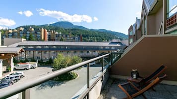 A hotel balcony with a view of a mountain, a parking lot, and a building with multiple windows.