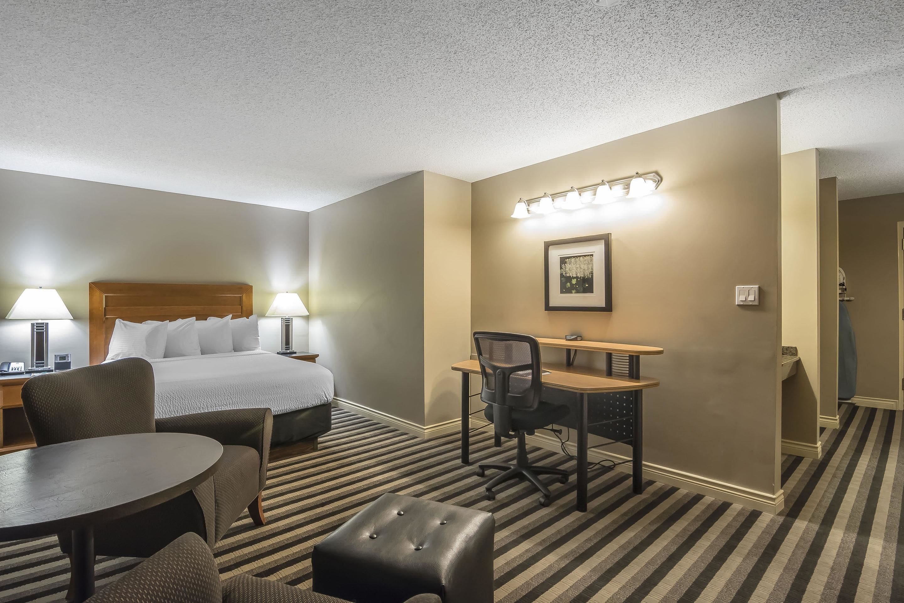 A hotel room with a bed, desk, chair, and table.