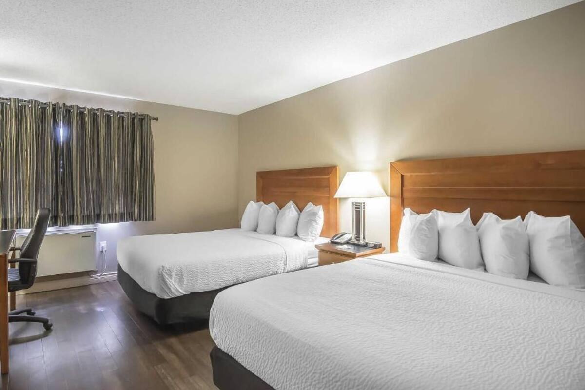 A hotel room with two beds, a desk, and a chair.