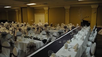A banquet hall with rows of tables set for a formal event, each with white tablecloths and chairs.