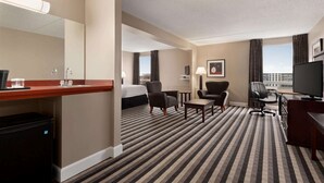 A hotel room with a bed, a desk, a chair, a TV, and a window with curtains. - Royal Hotel Regina, Trademark Collection by Wyndham (Regina)