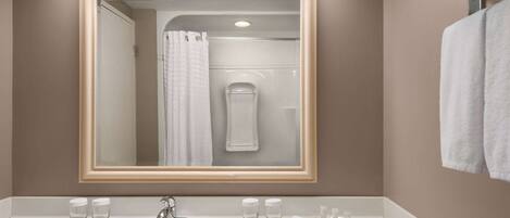 Un baño con un espejo grande, un lavabo y un perchero para toallas.