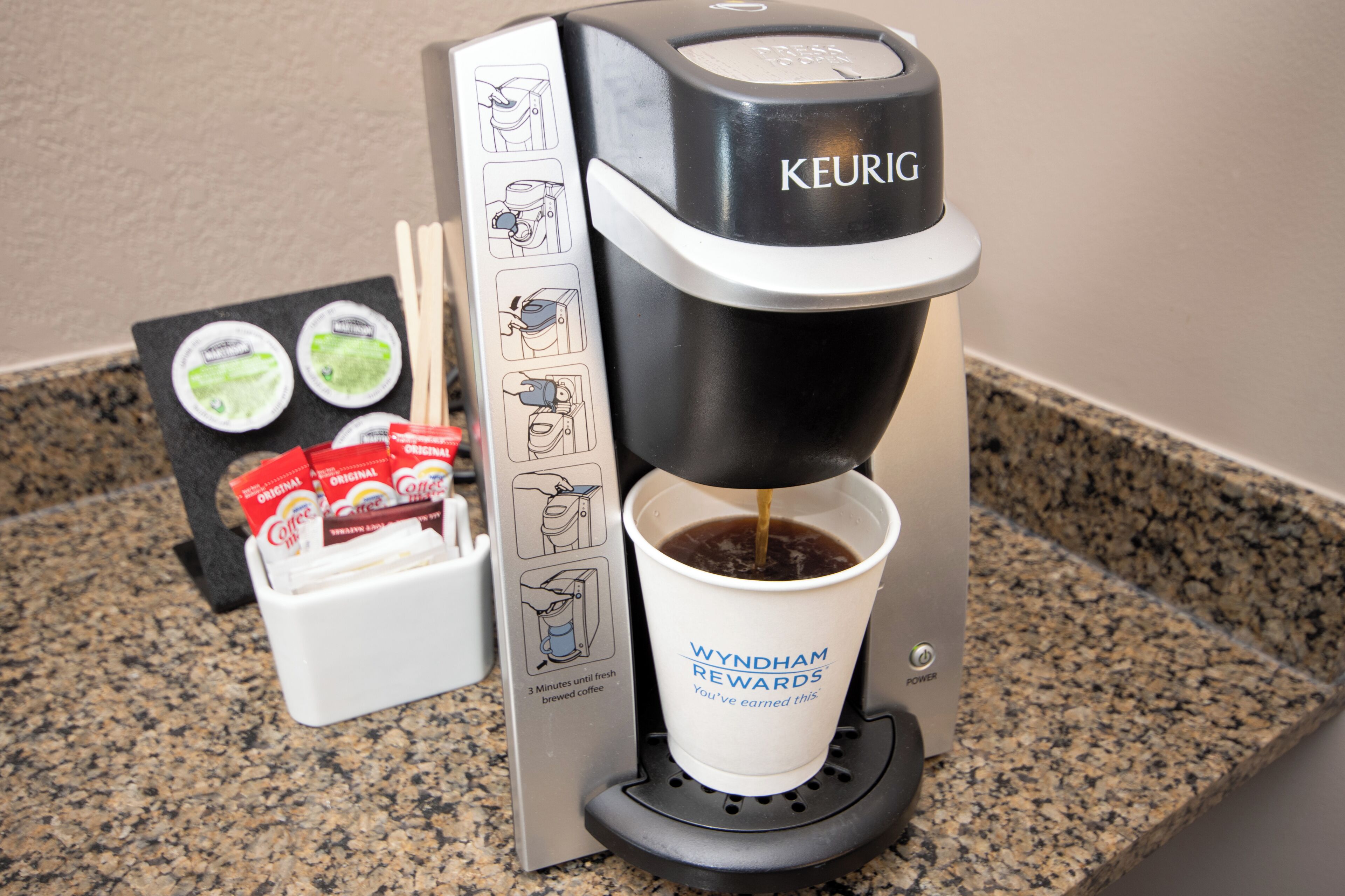 A Keurig coffee machine with a cup holder, a coffee pod holder, and a coffee pod.