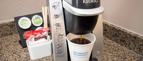 A Keurig coffee machine with a cup holder, a coffee pod holder, and a coffee pod.