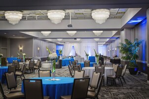 A conference room with round tables, chairs, and chandeliers.