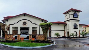 A hotel with a central entrance, a clock tower, and a parking lot with cars. - Serenity Stay (Chattanooga)