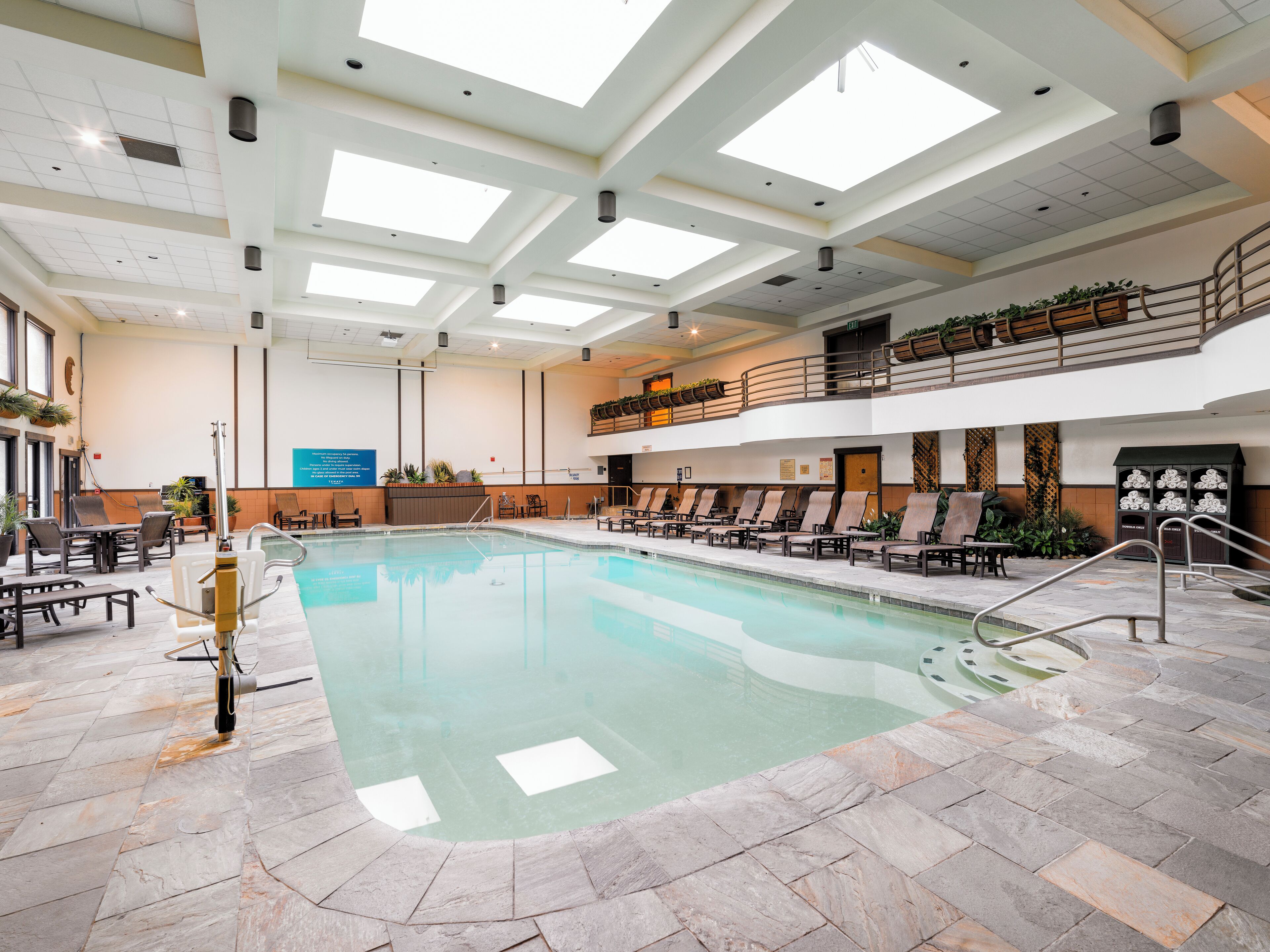 An indoor swimming pool with lounge chairs and a sun deck.