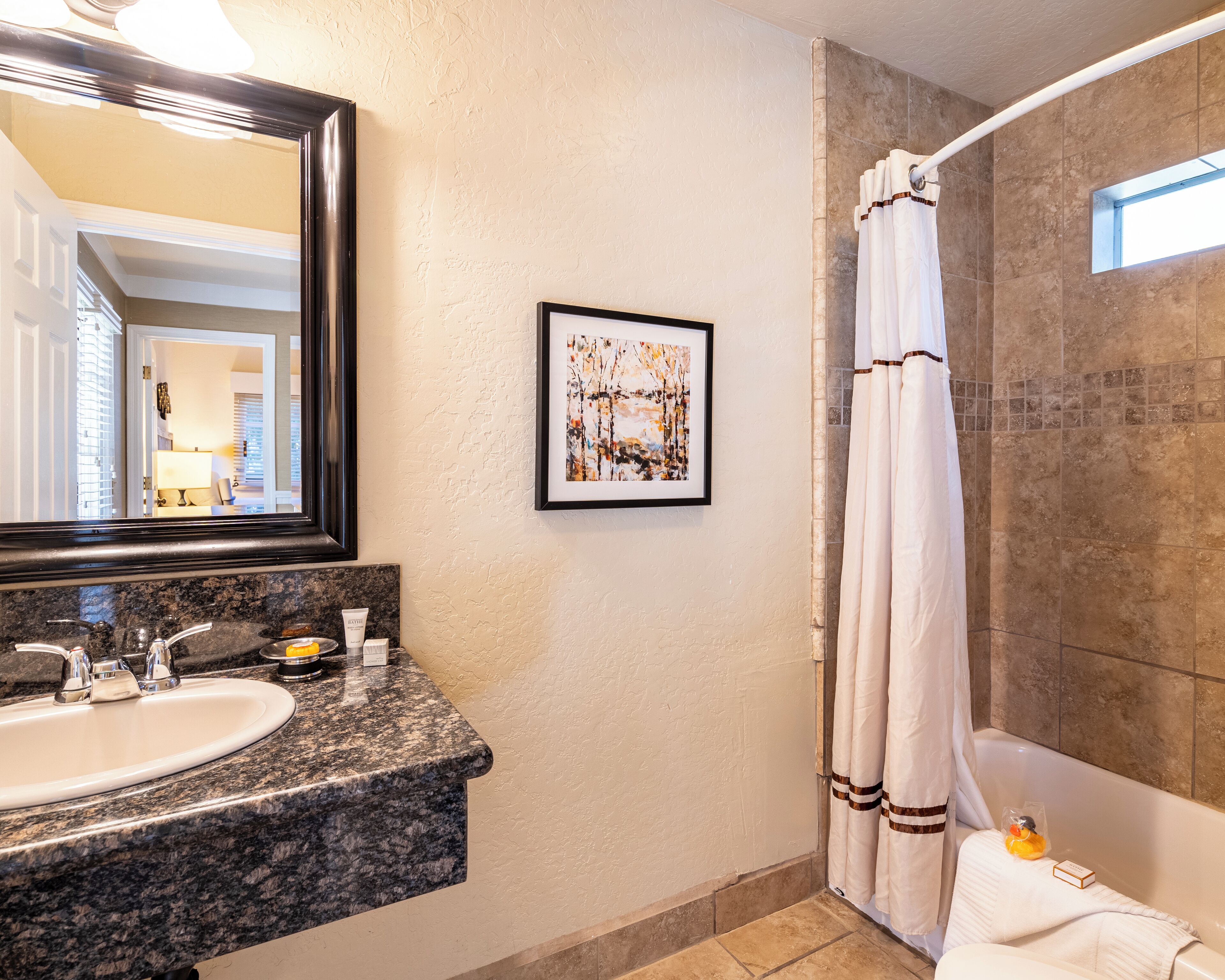Un baño con lavamanos, espejo, una obra de arte enmarco, cortina de ducha y bañera.