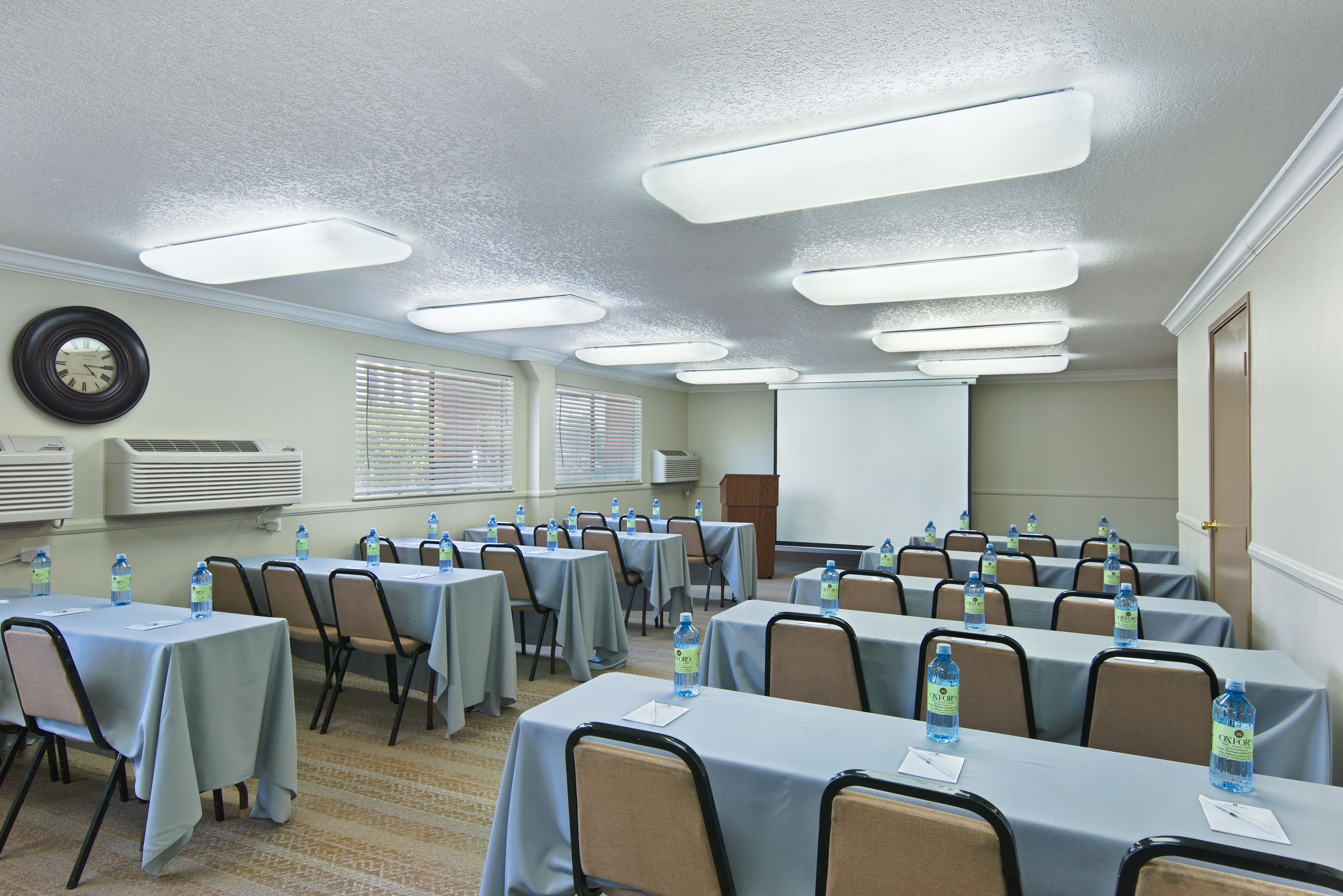 A conference room with multiple tables, chairs, and water bottles.