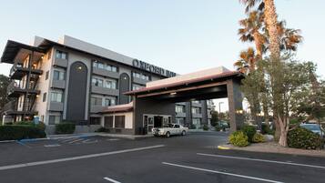 Een meerlaags hotel met een overdekte ingang en een parkeerplaats.