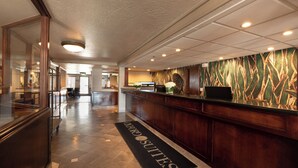 Uma área de recepção de hotel com balcão, tela digital e tapete com a inscrição 'Award Suites'.