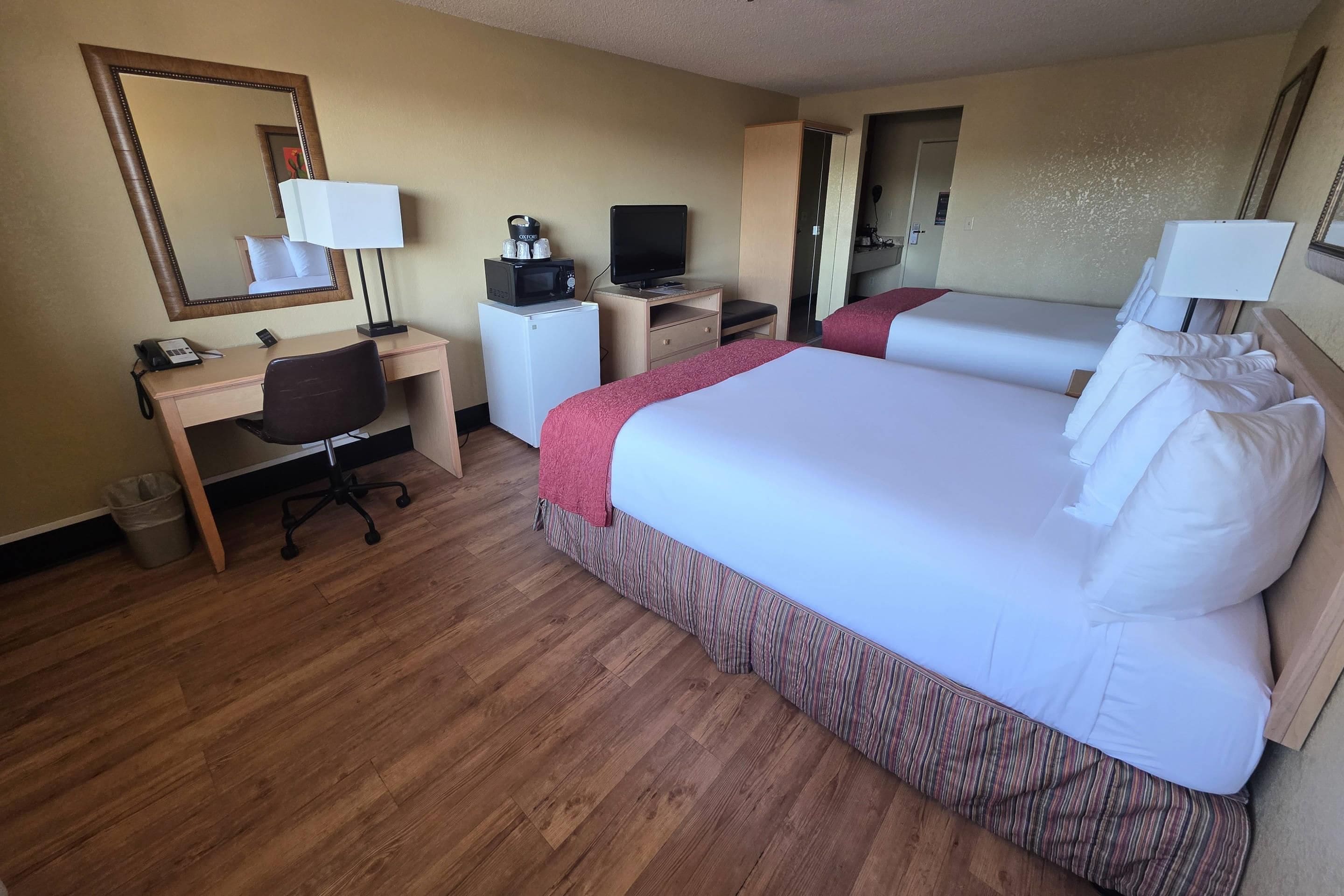 A hotel room with a bed, desk, chair, and a television.