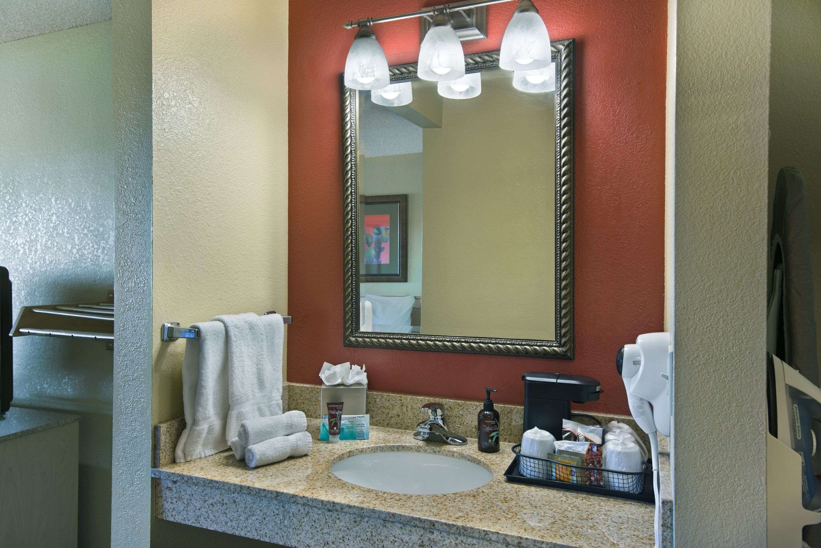 A bathroom with a granite countertop, a sink, a mirror, and a towel rack.