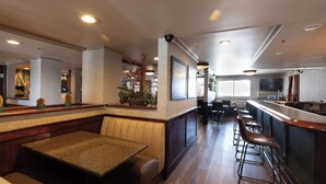 Um restaurante com área de bar, cabines e banquetas.