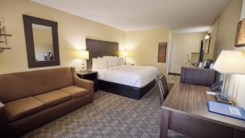 A hotel room with a bed, a sofa, a desk, and a mirror.