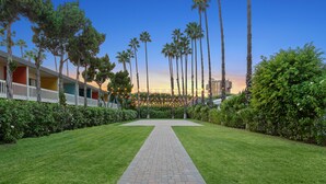 A pathway leading to a building with a row of palm trees and a clear sky. - The Anaheim Hotel (Anaheim)
