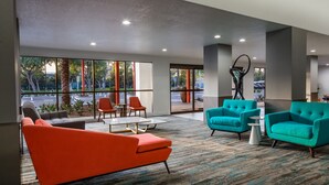 A modern lobby with large windows, orange and teal sofas, and a basketball hoop. - The Anaheim Hotel (Anaheim)