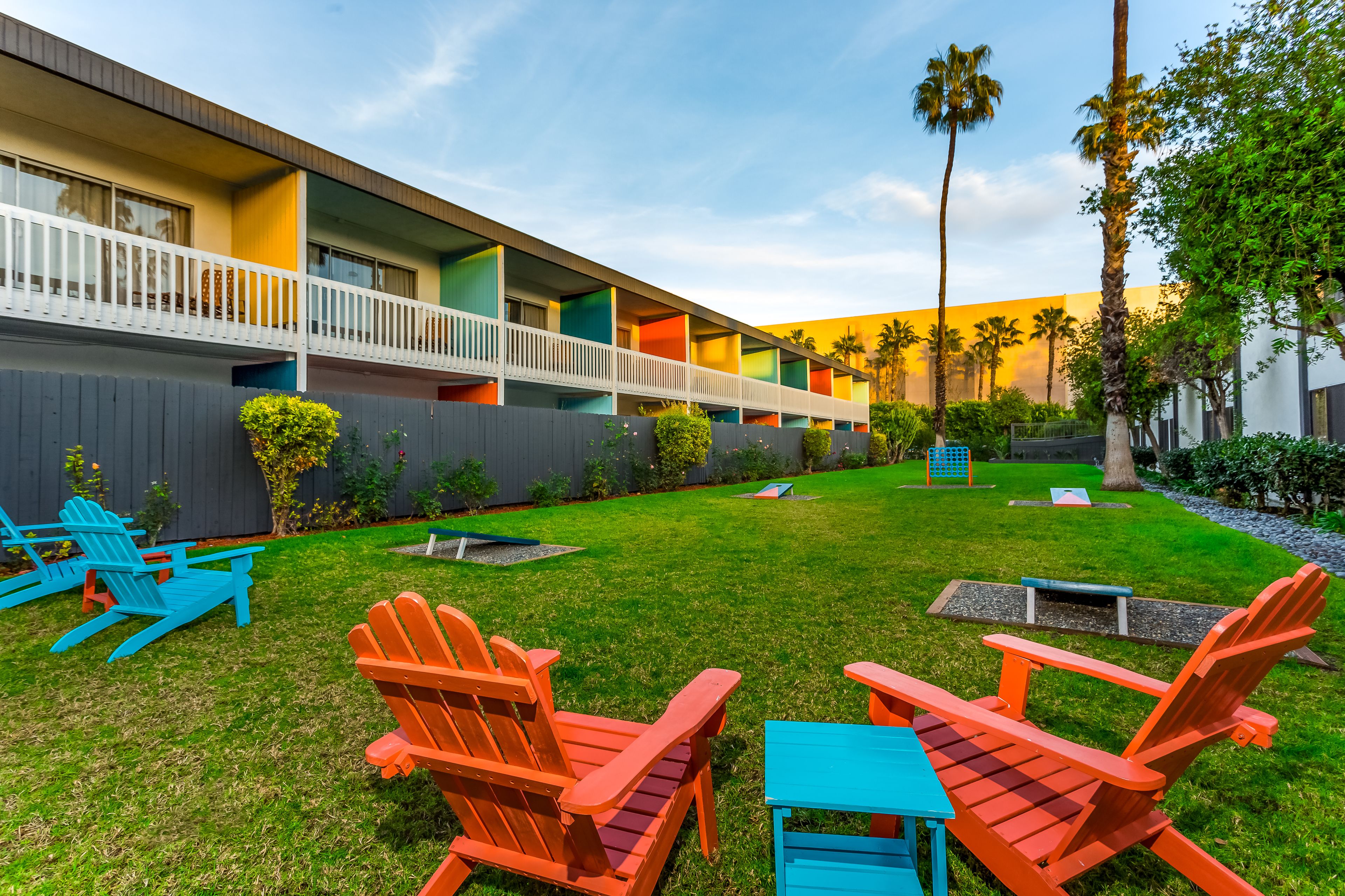A hotel with colorful balconies, a grassy lawn, and Adirondack chairs.