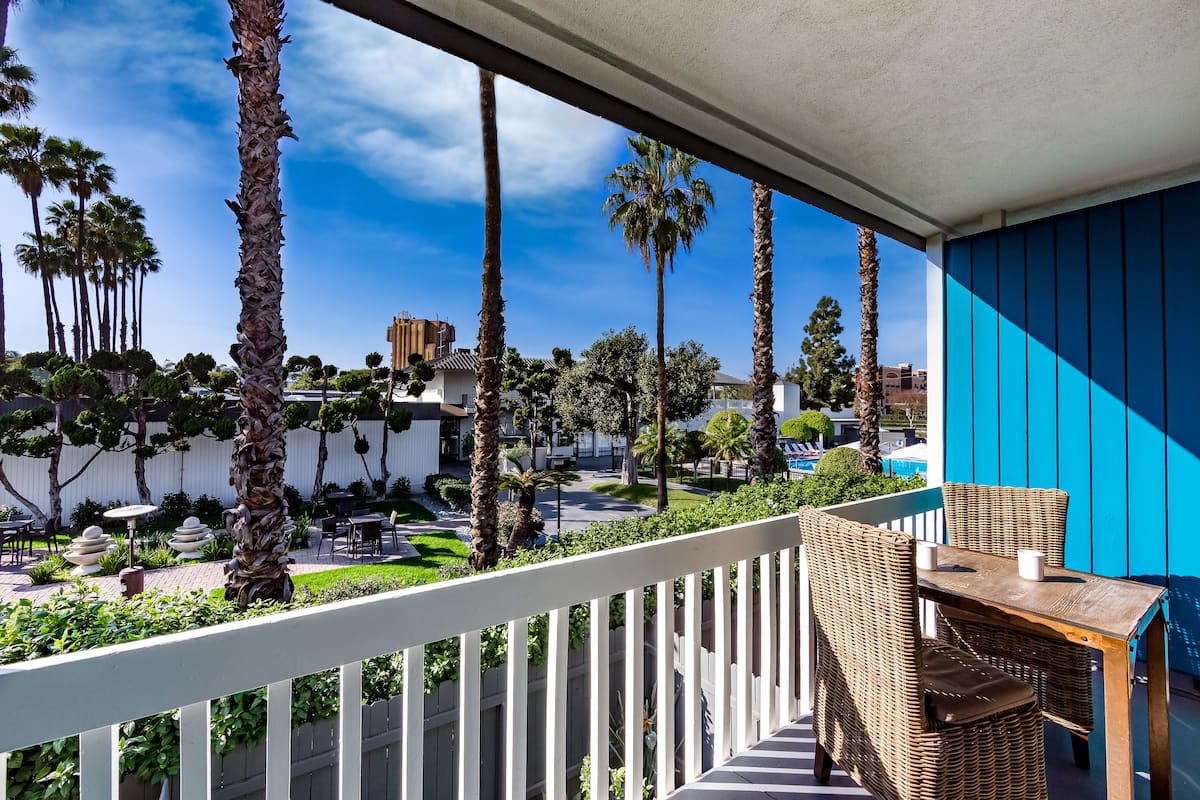 A balcony with wicker furniture and a view of palm trees and buildings.