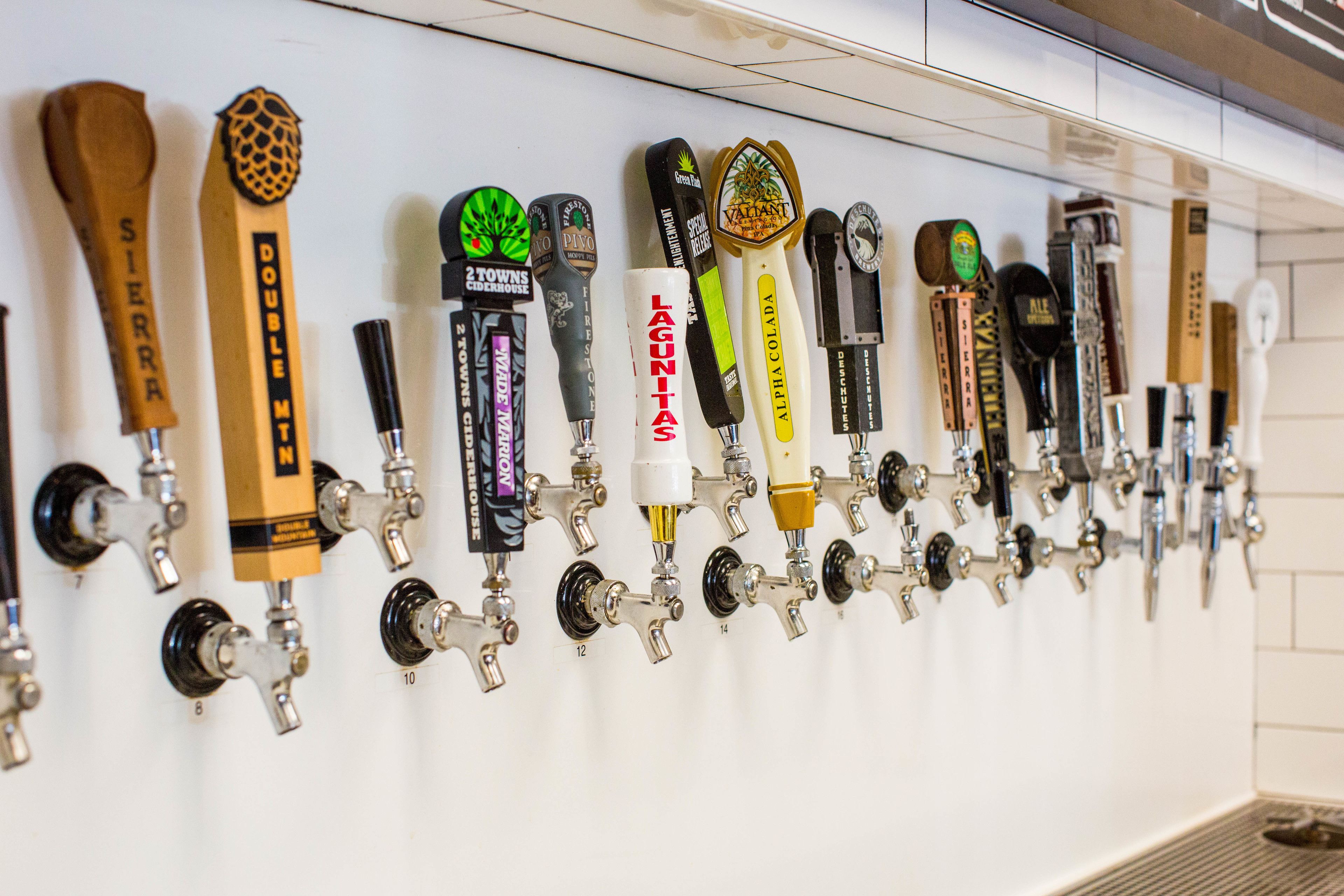 A row of beer taps with various labels and designs.