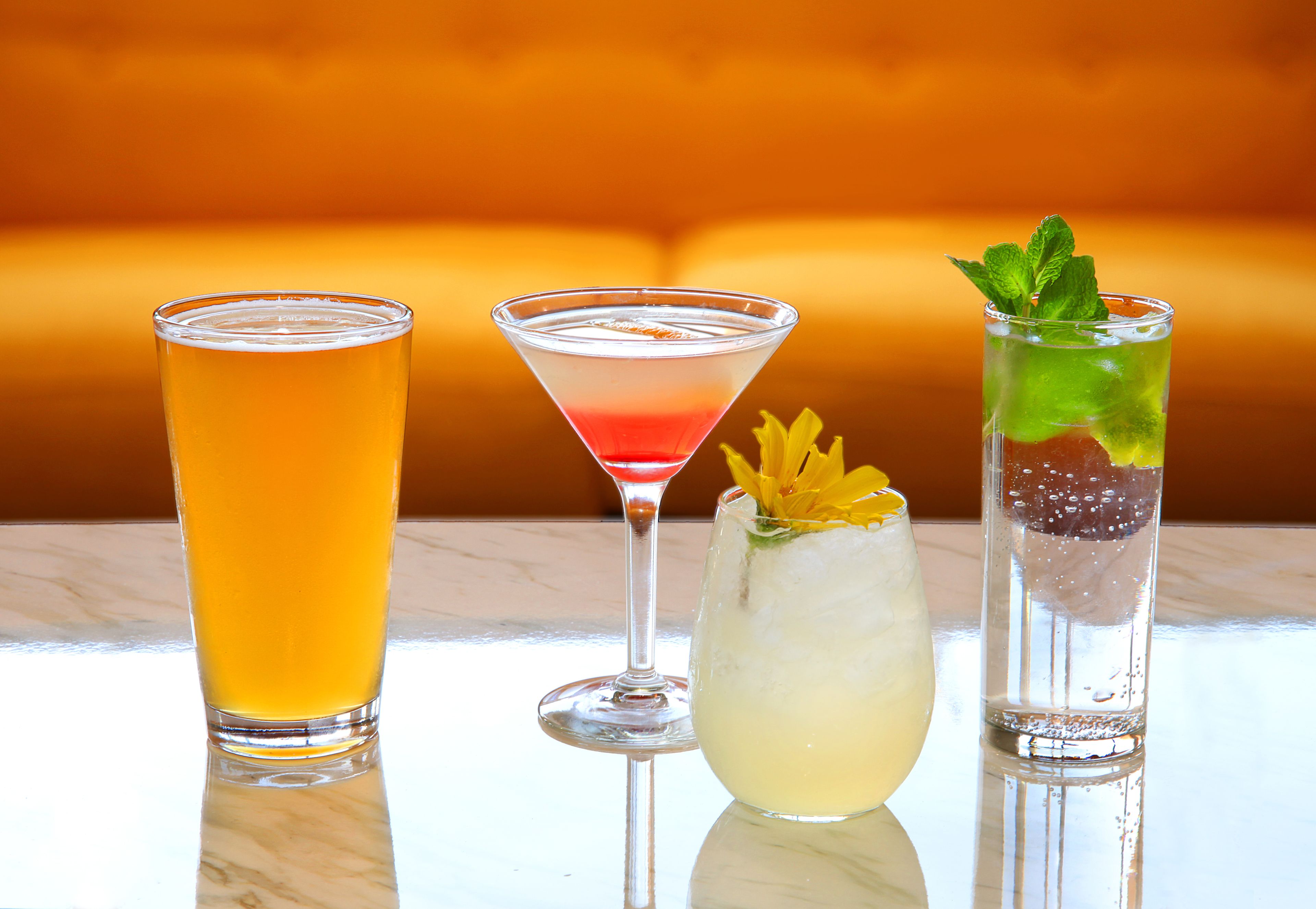 Three different drinks on a reflective surface with a warm-toned background.