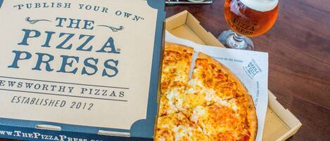 A pizza box with a pizza slice and a glass of beer on a wooden table.