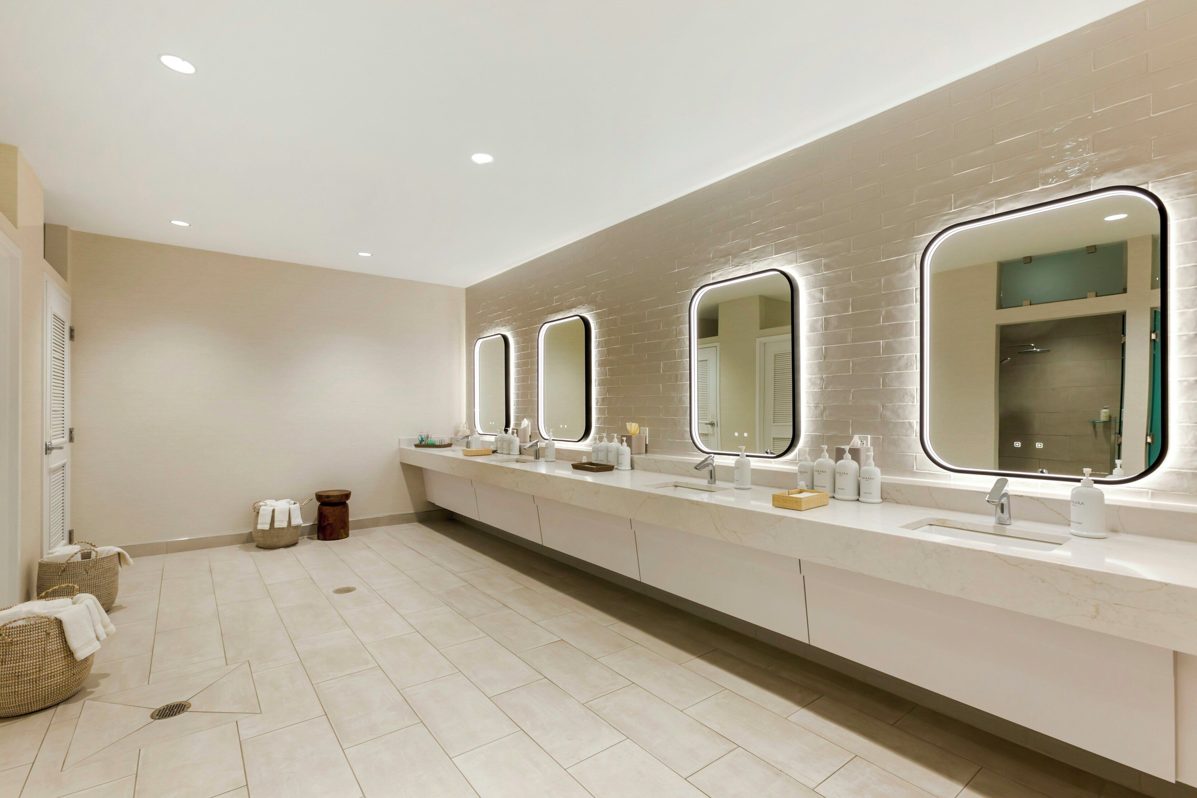 A modern bathroom with a long vanity, multiple mirrors, and a tiled floor.