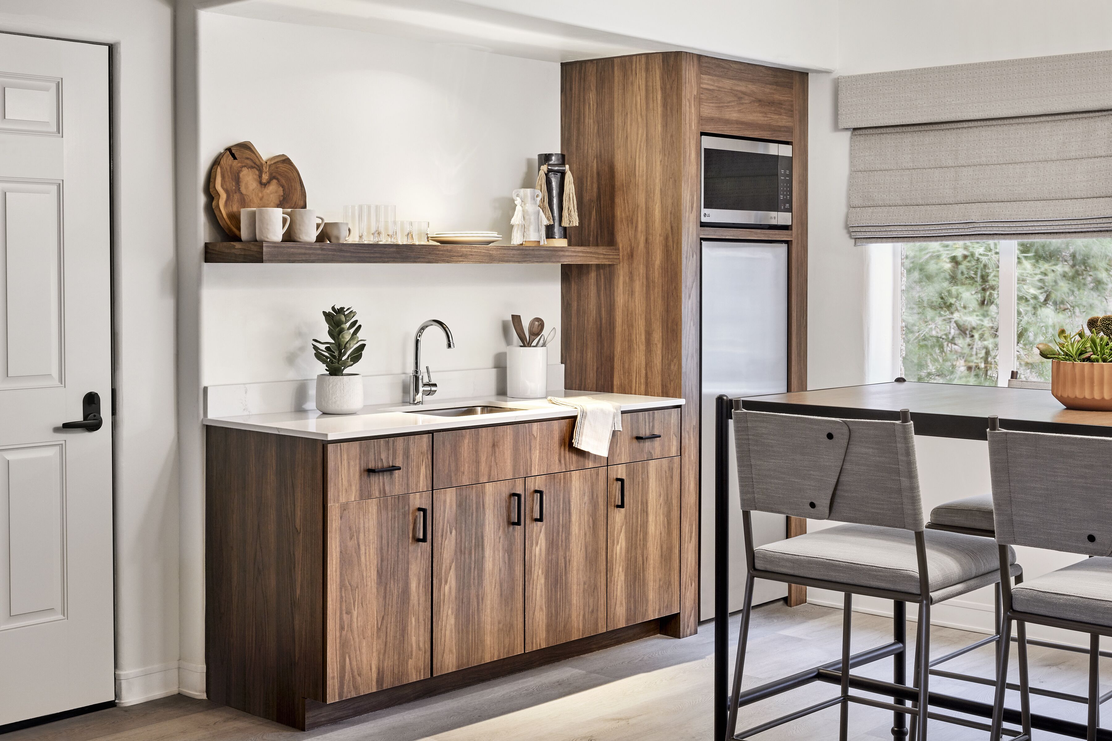 A modern kitchen with wooden cabinets, a stainless steel sink, and a dining area with two chairs.