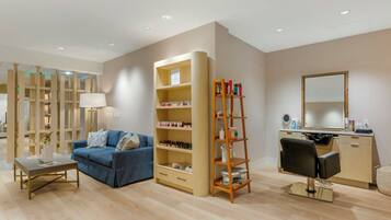 A modern living room with a blue sofa, a wooden bookshelf, a desk, and a mirror.